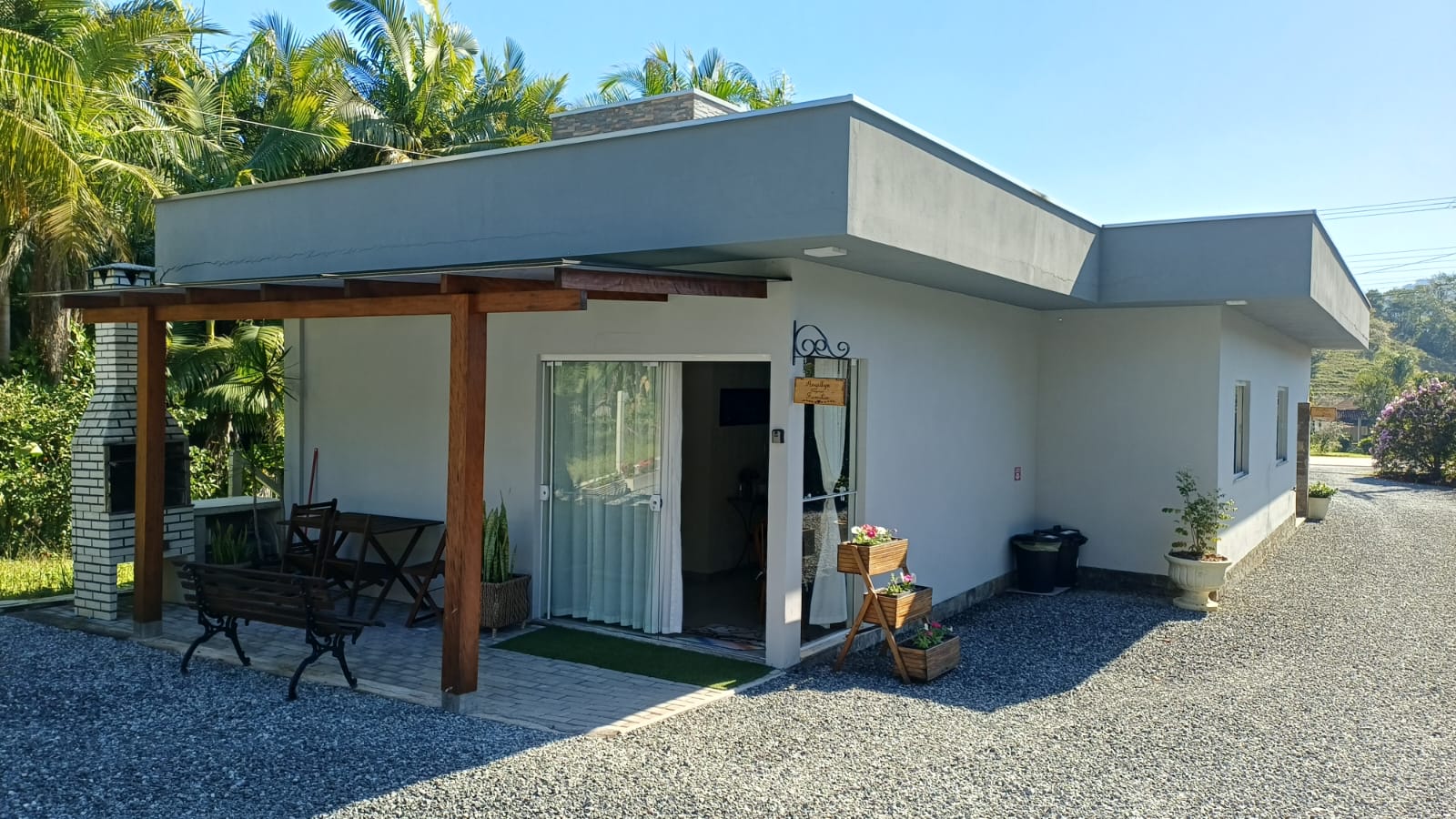 Fachada da hospedagem com varanda e pátio de cascalho